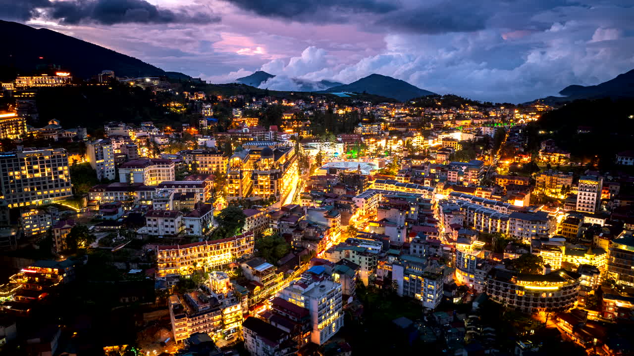 Drone twilight hyperlapse over illuminated Sa Pa in Vietnam with rolling clouds