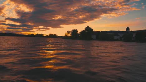 A-boatride-on-the-historic-steam-boat-Ludwig-Fessler,-built-in-1927,-across-the-Chiemsee-lake-in-Bavaria,-home-to-King-Ludwig-II-of-Bavaria's-Versaille-replica-castle-on-an-island-by-sunset