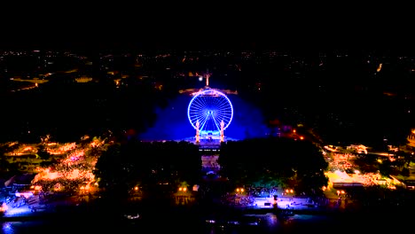 rueda gigante iluminada por la noche durante la feria del vino y la multitud cercana en burdeos, francia, tiro de inclinación aérea hacia arriba