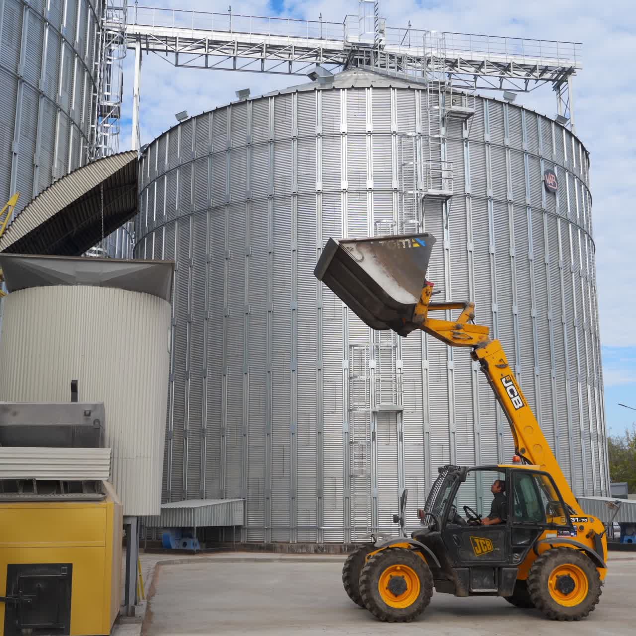 Silver silos on agro manufacturing plant for storage of agricultural products. Large iron barrels of grain. Granary elevator