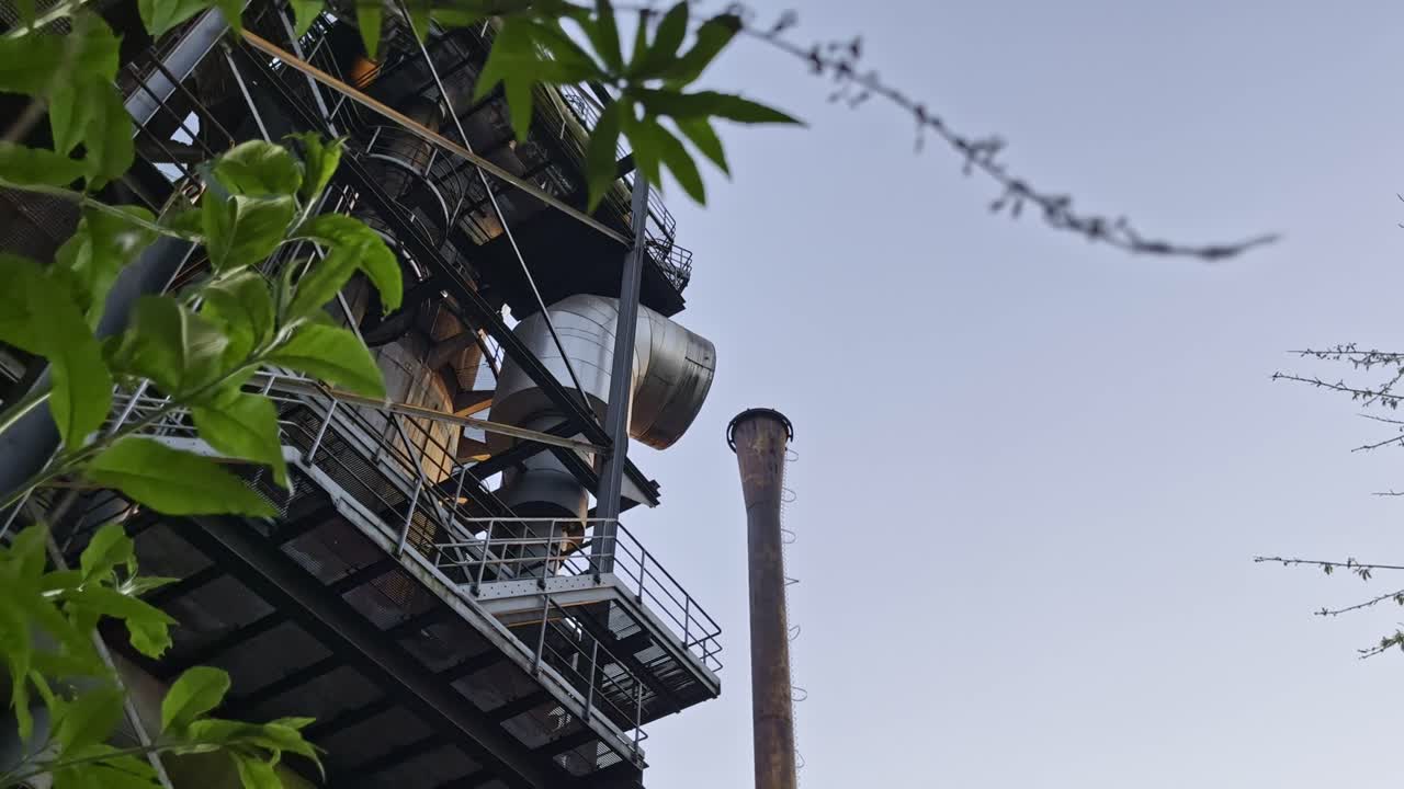 독일 듀스부르크의 옛 산업단지 건물, 철강 생산을 위한 파이프와 자연이 전면에 있습니다.