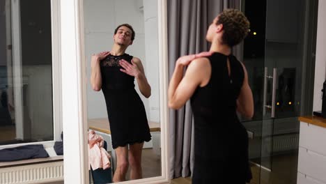 a man in little black dress in front the mirror sensually moves