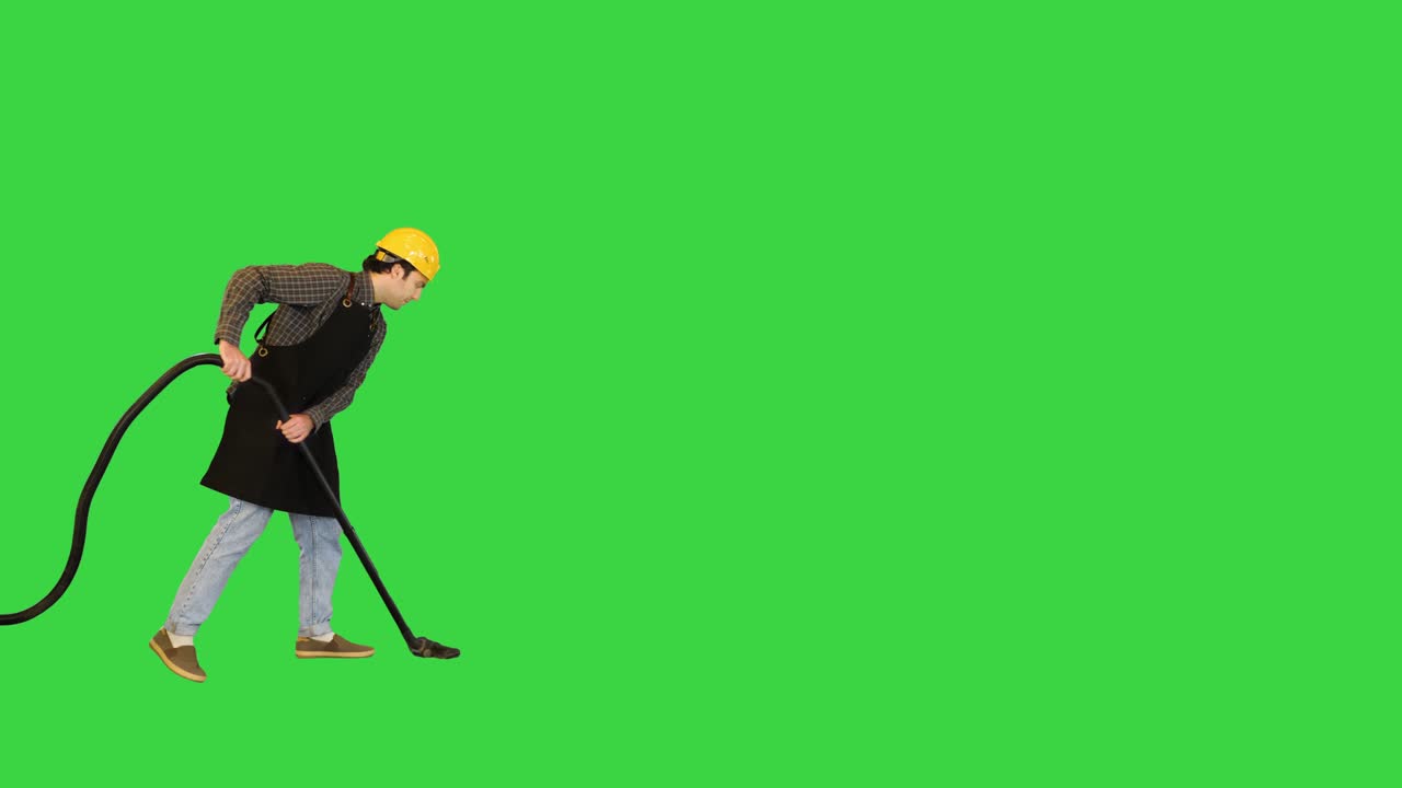 trabajador de la construcción trabajando en el sitio con una aspiradora y sonriendo a la cámara en una pantalla verde, clave de croma