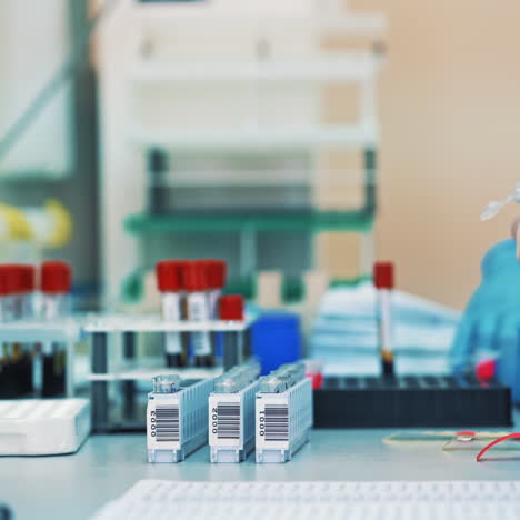 medical workers put blood samples in tube onto a special rack in clinic. women scientists in protective gloves are working in modern pharmaceutical laboratory.
