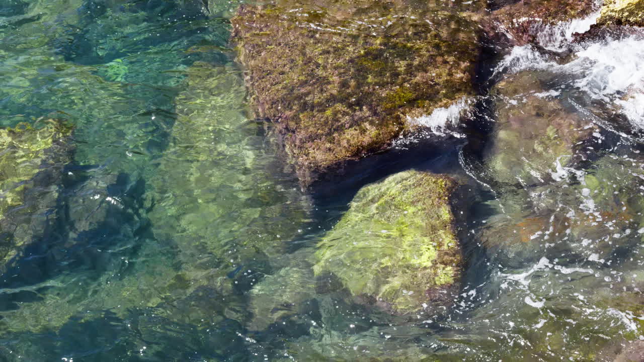 Clear Turquoise Ocean Water with Waves Crashing on Rocks