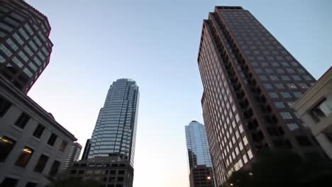 this captures the stunning urban landscape of downtown with towering skyscrapers touching the evening sky, illuminated by streetlights as day turns into night.