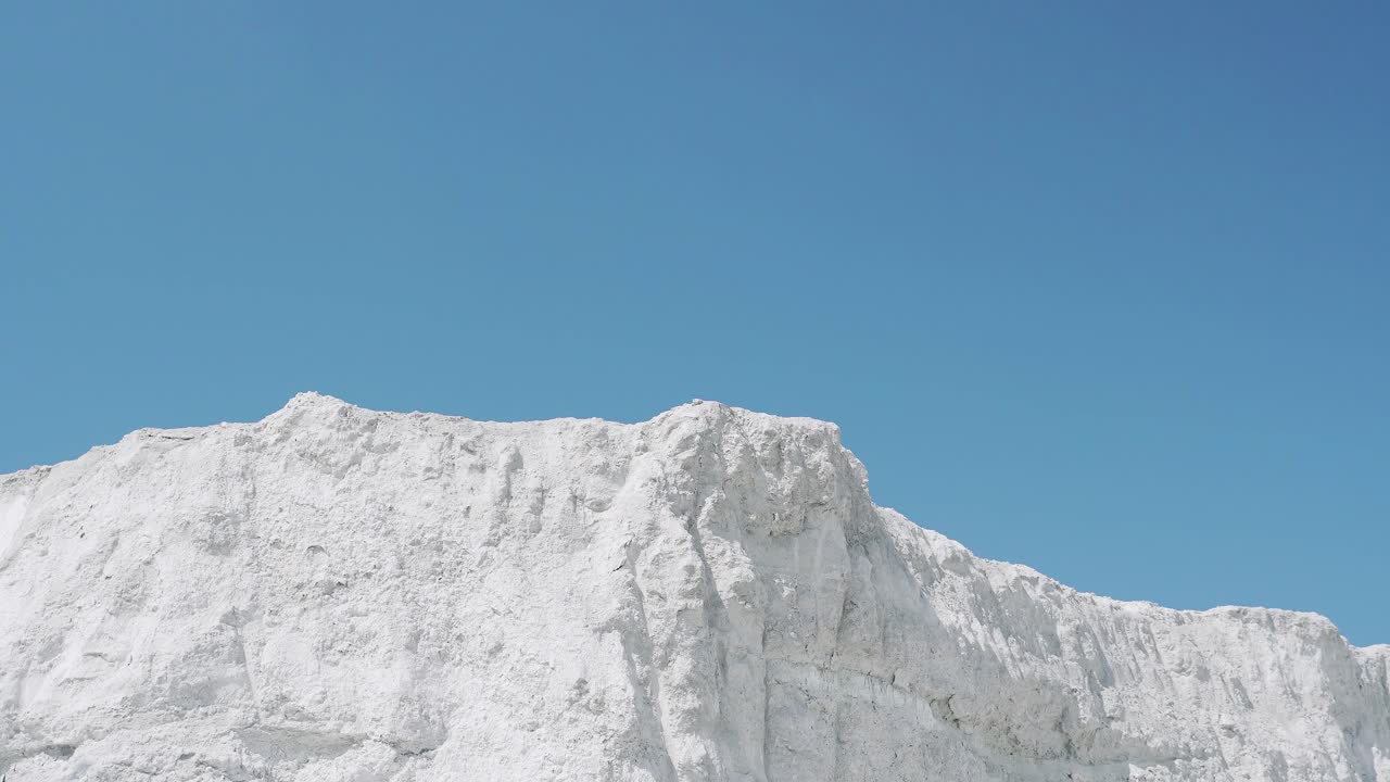 Male athlete runs on a white mountain raising hands up. Victory celebration
