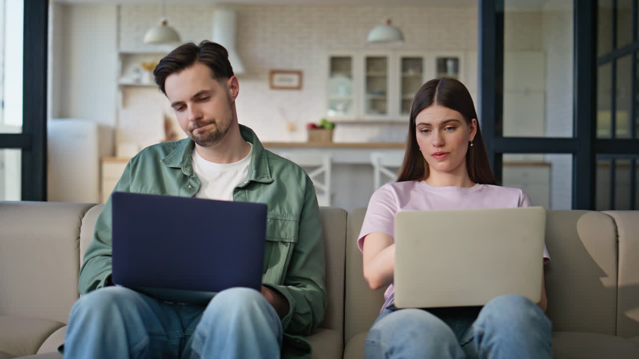 Serious friends discussing computer screen talking together at couch closeup
