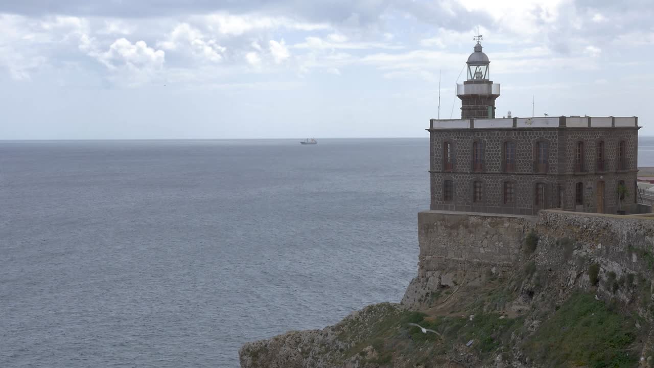 faro de melilla con el mar mediterráneo en el fondo y un barco de carga
