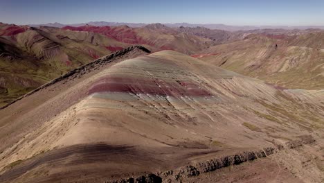 las vibrantes capas de rojo, verde y marrón crean una impresionante vista de la cordillera del perú bajo un cielo azul brillante.