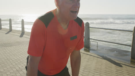hombre mayor tomando un descanso de correr en el paseo marítimo