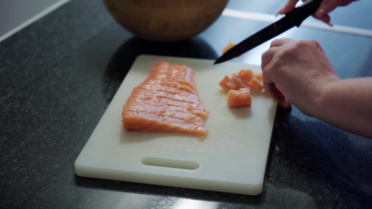 Close up shot of woman hands cutting raw salmon in slices, interior