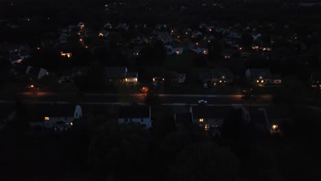 lighting houses in quiet neighborhood at night. american residential area in suburb of american town. descending drone wide shot.