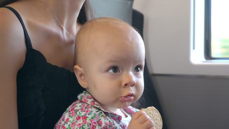 a baby eating a biscuit on the train