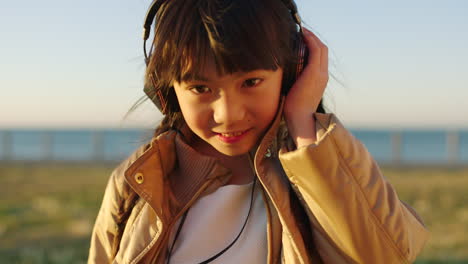 Face,-music-headphones-and-Asian-kid-at-beach-park