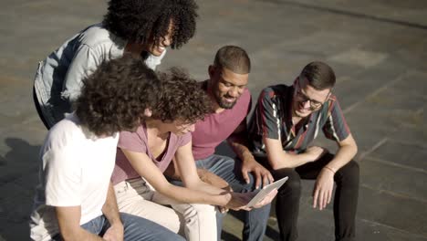 laughing young friends watching funny video on tablet.