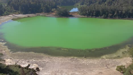 aerial birds eye shot of green colored telaga warna lake during sunny day surrounded by woodland in indonesia