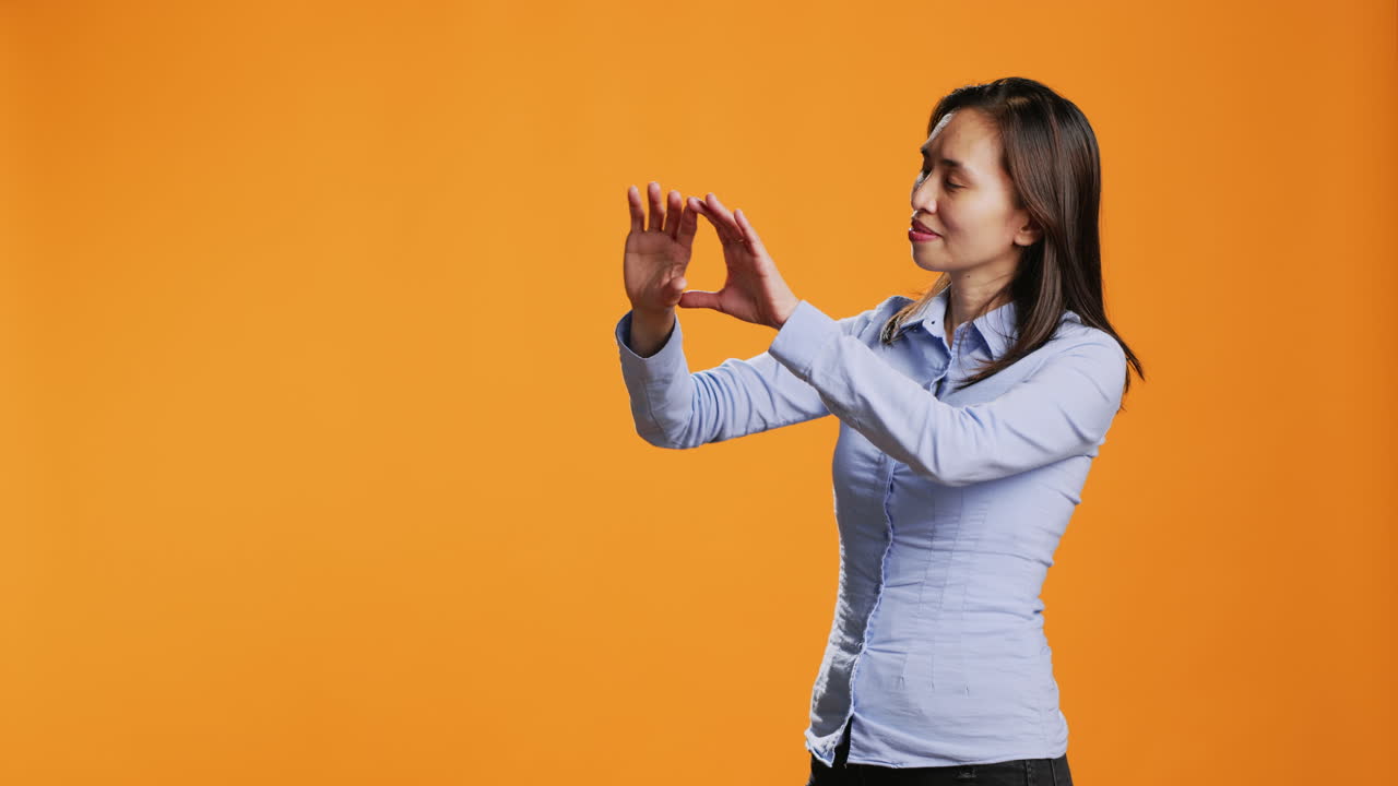una mujer asiática examina el reflejo de una imagen holográfica en un estudio.