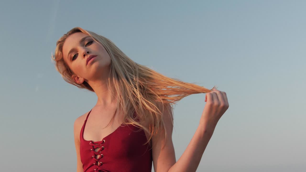 해변에서 빨간 수영복을 입고 포즈를 취하는 젊은 금발