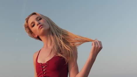 joven rubia posando en un traje de baño rojo en una playa