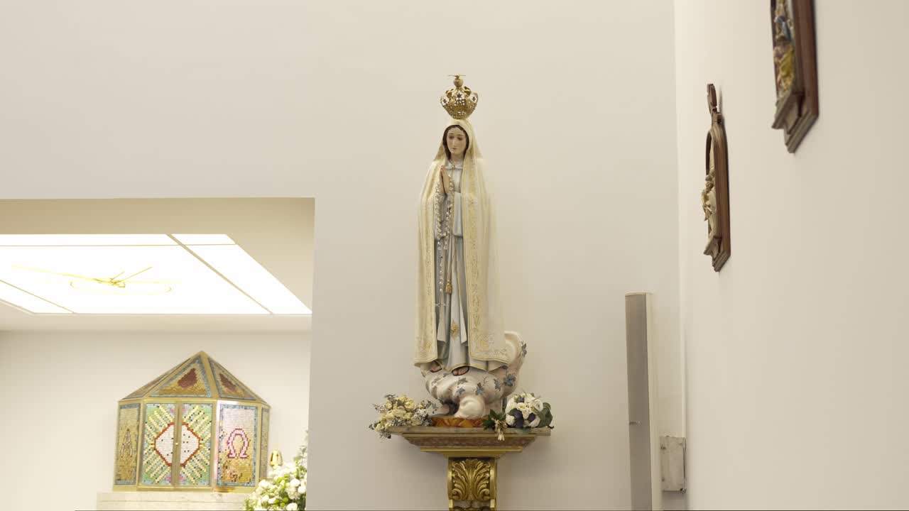 Full view of crowned Virgin Mary statue on ornate pedestal in bright chapel interior