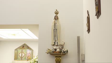 full view of crowned virgin mary statue on ornate pedestal in bright chapel interior