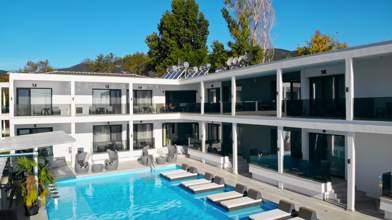 ASPROVALTA, GREECE - SEPTEMBER 25, 2020: Luxury Resort from the drone. Pool with blue water, sunbeds, main building with multiple hotel rooms and terraces, greenery around it