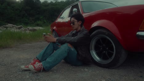 man sitting by a vintage red car