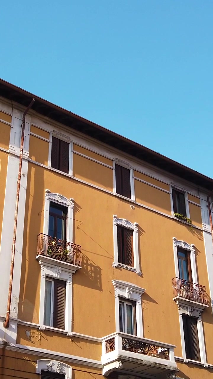Vista panorámica vertical en ángulo contrapicado de la fachada de coloridos edificios residenciales amarillos en Milán, Italia