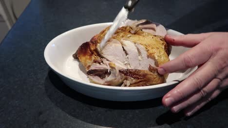 man cutting or carving a hot roast chicken