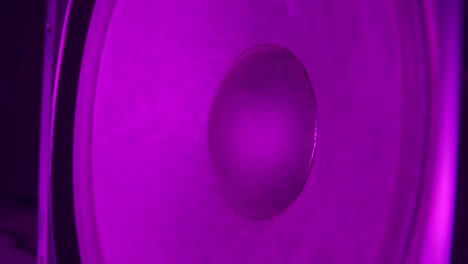 a vibrating color woofer. a big loud speaker in action. color changing big woofer. close up. slow motion