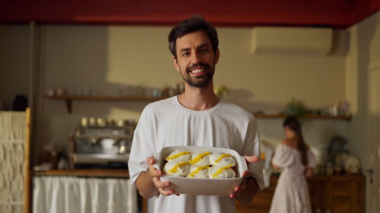 hombre sosteniendo una bandeja de pasteles deliciosos en la cocina