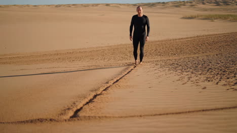 man walking barefoot on sand dunes
