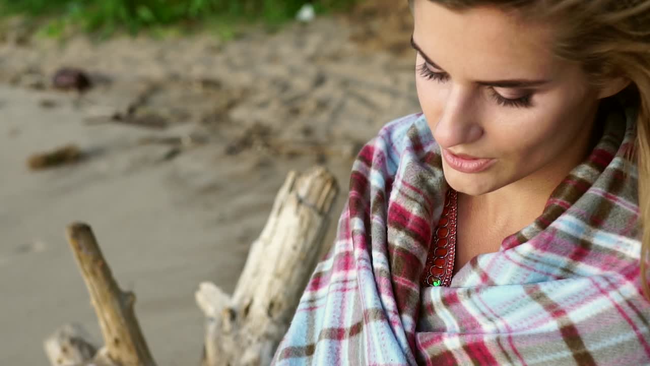 Donna con una coperta a quadri su una spiaggia