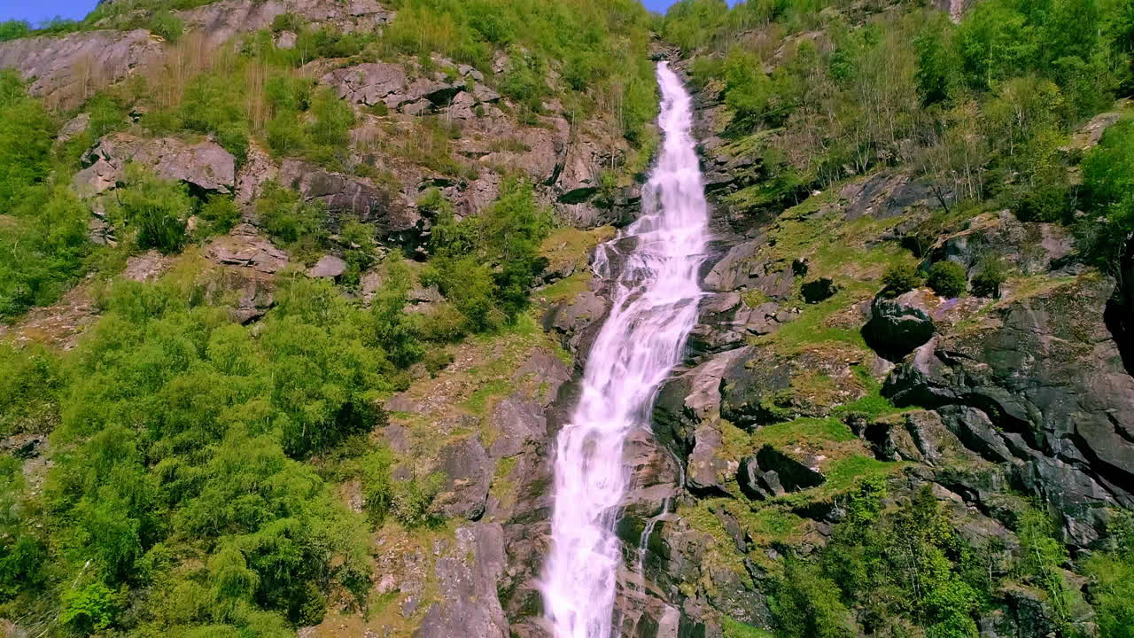 toma en ángulo bajo de una hermosa cascada en las montañas rocosas en aurland, noruega en un hermoso día soleado con el cielo azul de fondo