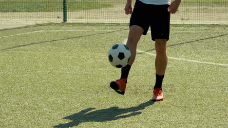 close up of an unrecognizable soccer player training freestyle tricks with the ball on a street football pitch on a sunny day 1