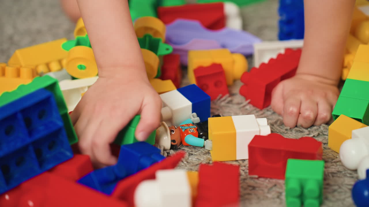 Niño explora bloques sensoriales. Niño investiga con entusiasmo una colección de objetos táctiles coloridos. Un niño emocionado interactúa con una pila de bloques de construcción texturizados y de colores vivos en el suelo.