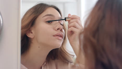 pretty woman applying mascara with brush