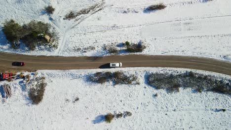 aerial view of a van driving at a crossroad in rural landscape corered with snow on a sunny winter day, dalmatian, croatia