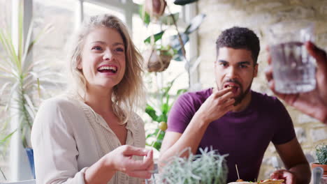 multi-ethnic group of friends laughing at lunch in a restaurant, selective focus