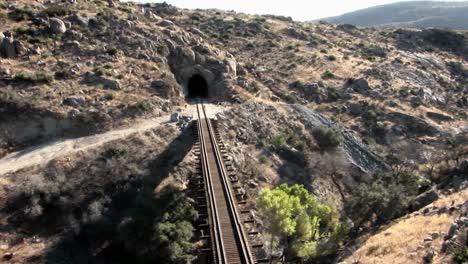 smoke rises as an indication that a train is coming across a bridge and heading for a tunnel