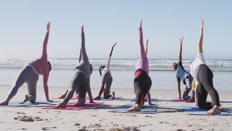 Multiethnische-Gruppe-Von-Frauen,-Die-Yoga-Position-Am-Strand-Und-Im-Hintergrund-Des-Blauen-Himmels-Machen