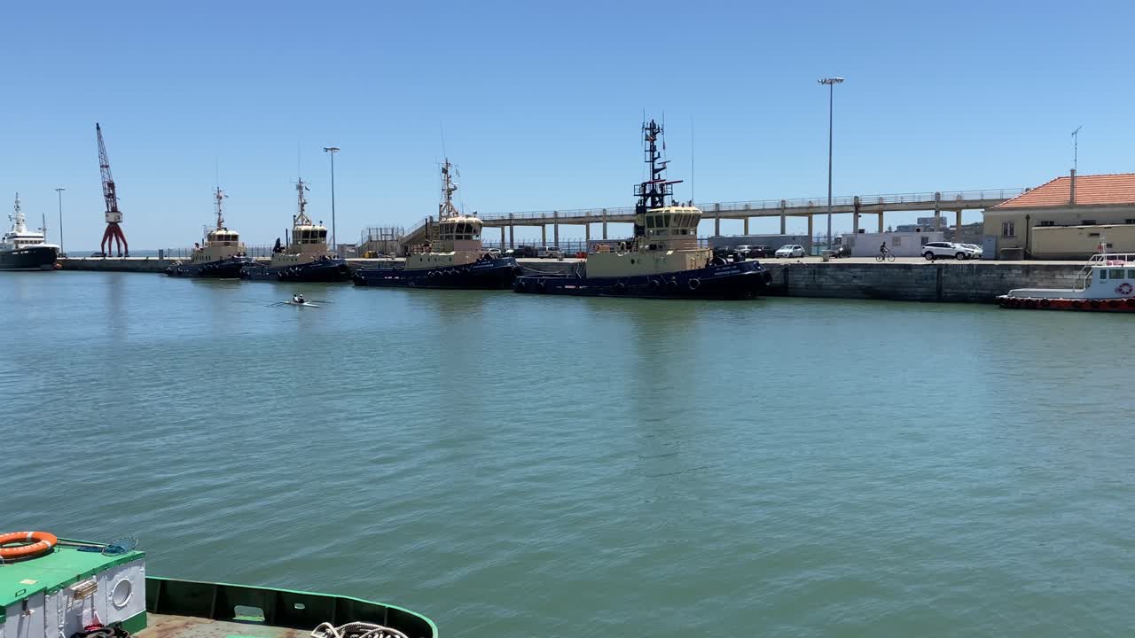 una pareja de amantes navegando en canoa por el puerto marítimo de alcántara en un día soleado con algunos barcos de las fuerzas armadas al fondo