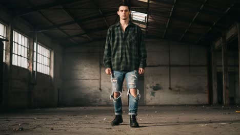 a solitary figure walks through an abandoned warehouse, showcasing urban fashion with ripped jeans and a flannel shirt, encapsulating a mood of introspection and loneliness.