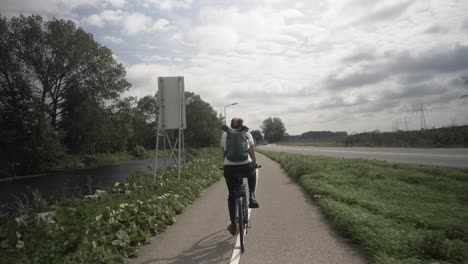 woman cycling on road in a typical dutch village countryside