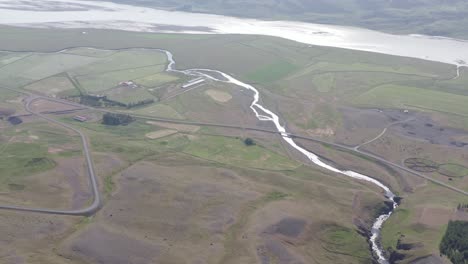 Estuary-meandering-towards-large-river-in-Iceland-valley,-aerial