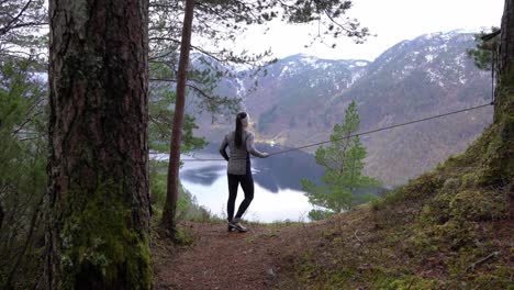 woman stops at scenic viewpoint overlooking norwegian fjord while hiking