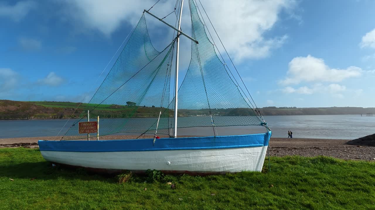 Restaureret fiskebåd i den traditionelle fiskerby Passage East med mennesker på stranden, Episk Waterford, Irland.