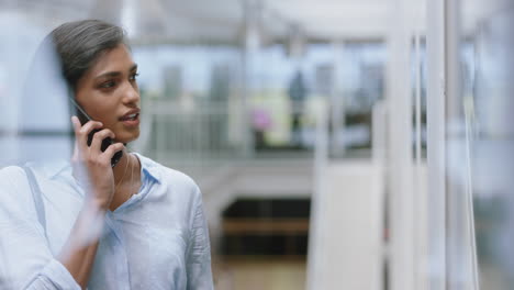 hispanic business woman using smartphone having phone call chatting on mobile phone enjoying conversation with client at work in office