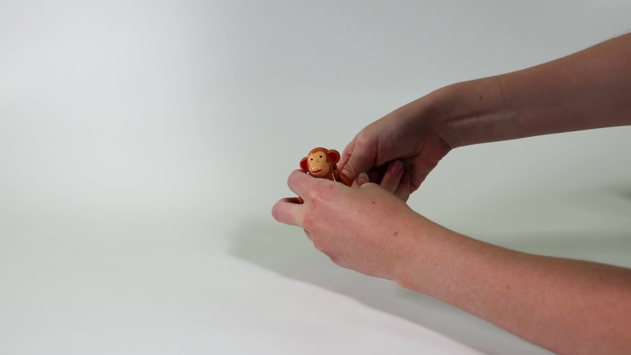 las manos manipulan un mono de juguete en la mesa